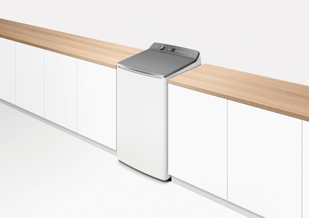 Top loader washing machine integrated into a white cabinet and wooden countertop