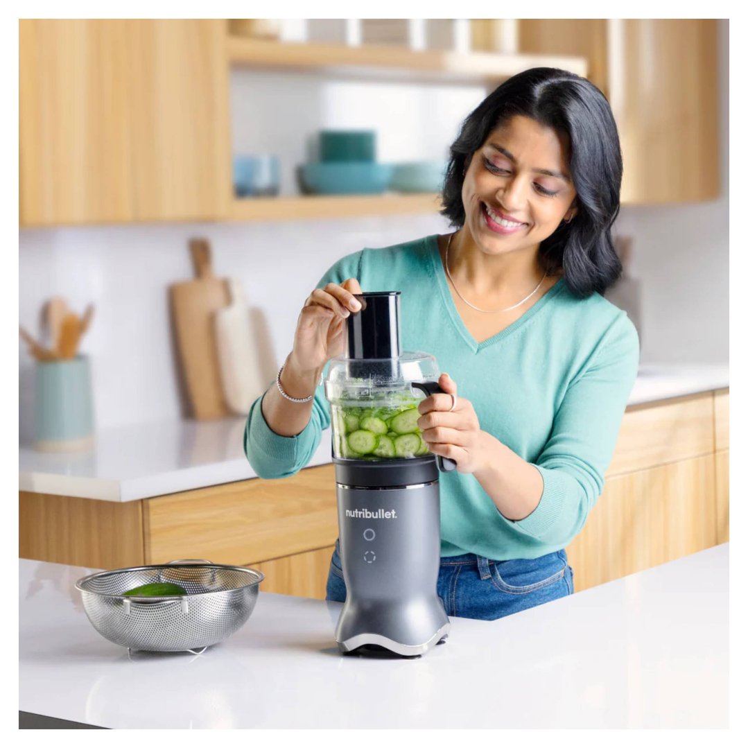 Woman using a Nutribullet blender to slice cucumbers in a kitchen