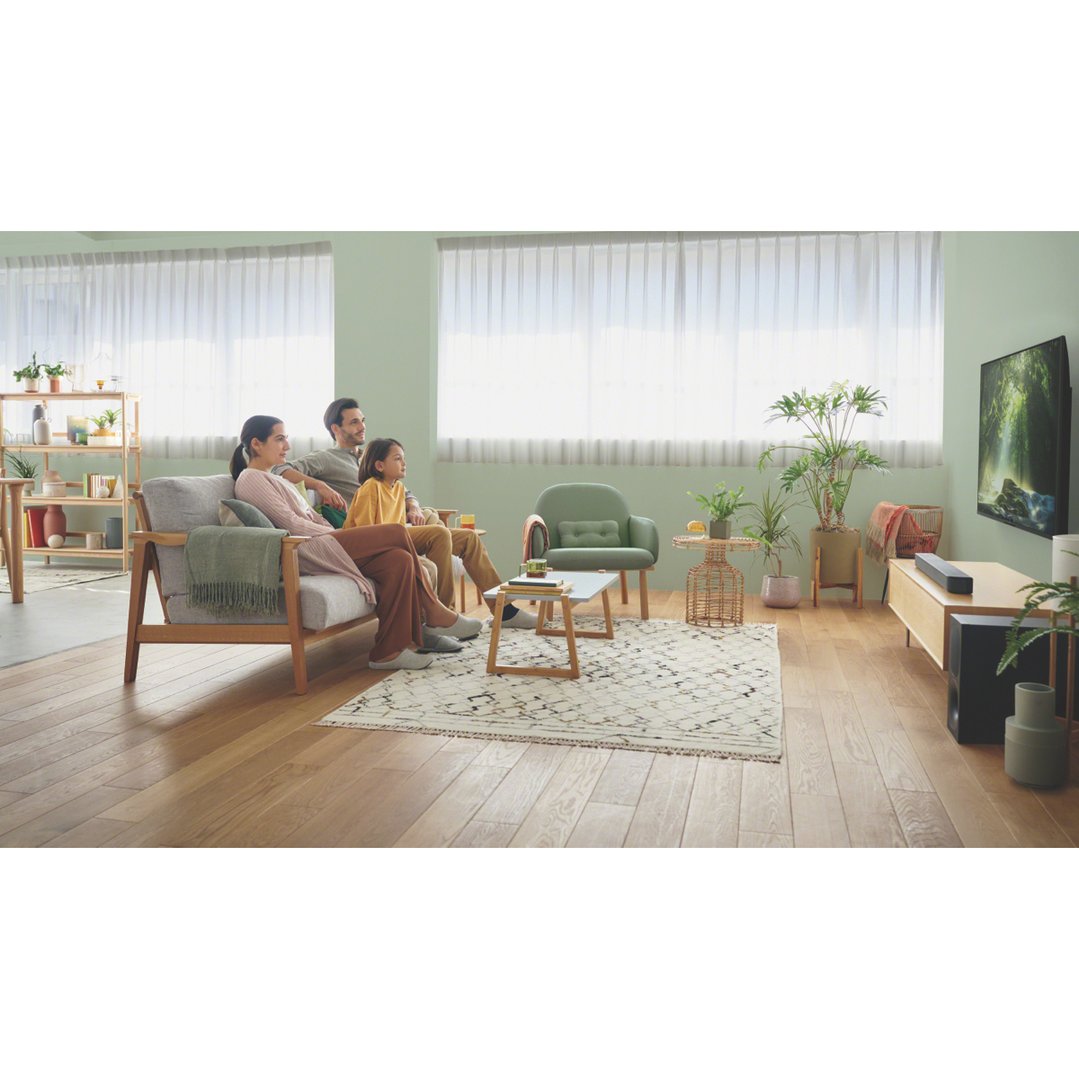 Family watching TV with a soundbar and subwoofer in a living room