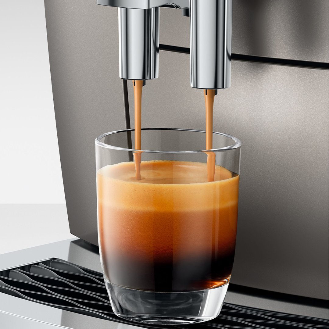 Coffee machine dispensing two streams of coffee into a glass