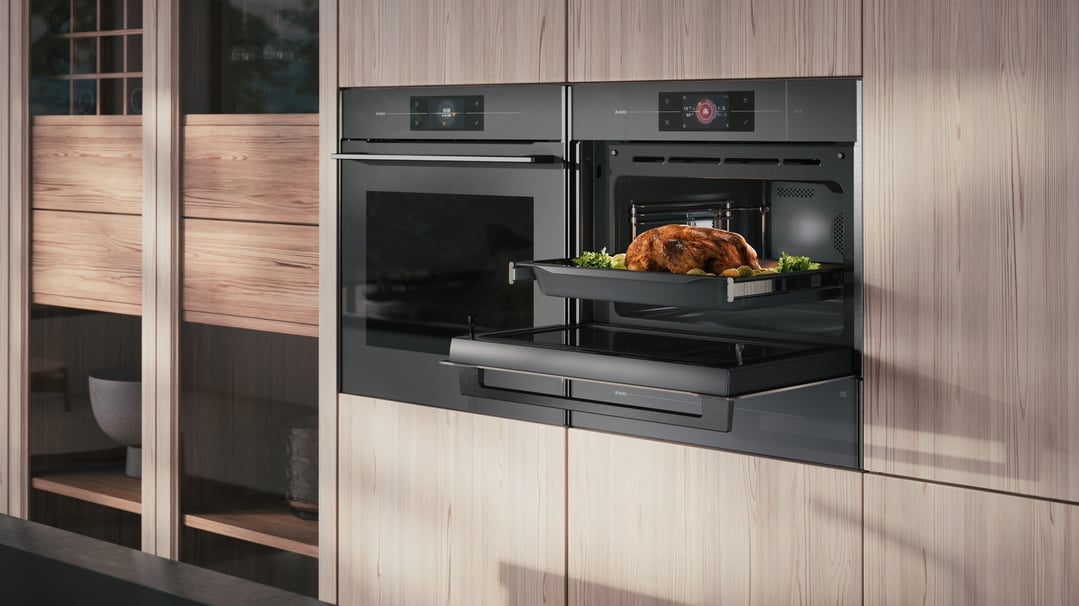 Two built-in ovens in a kitchen, one with a roasted chicken inside