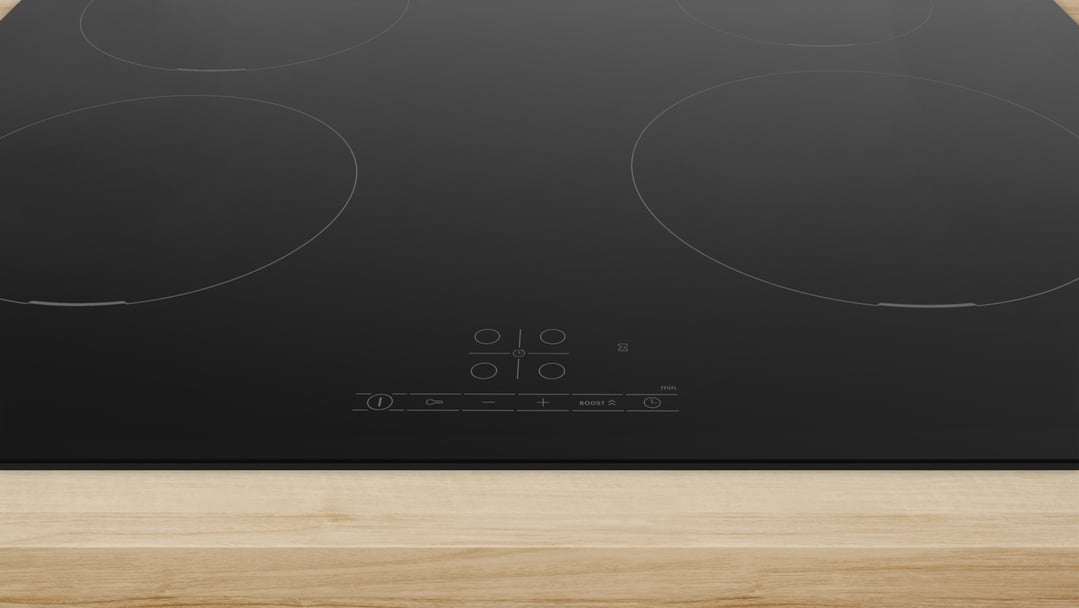 Black induction cooktop with controls on a light wooden countertop