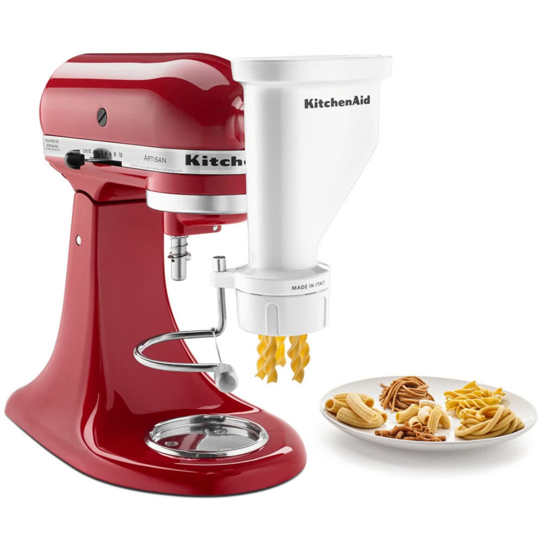 Red KitchenAid stand mixer with pasta press attachment making pasta, with a plate of pasta
