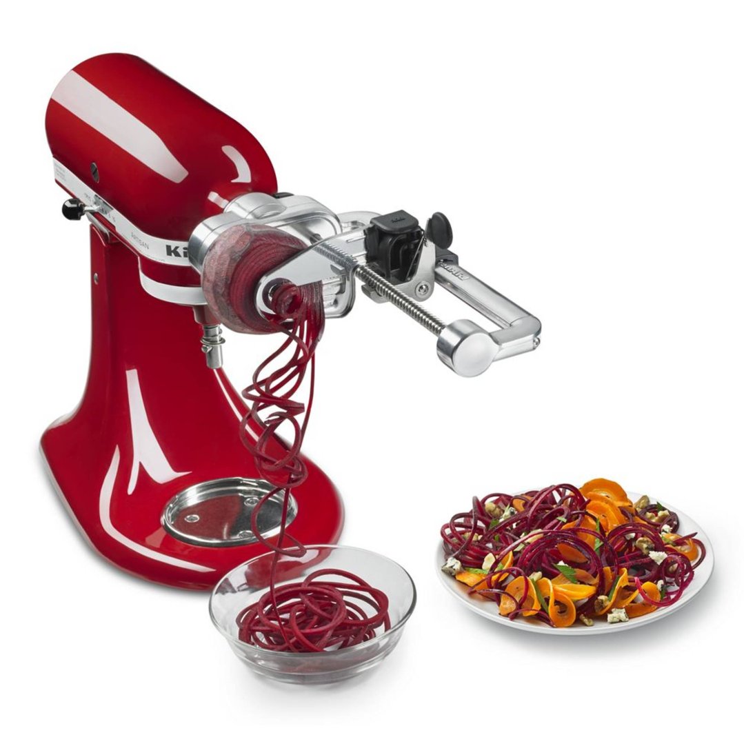 Red KitchenAid stand mixer with spiralizer attachment making vegetable noodles