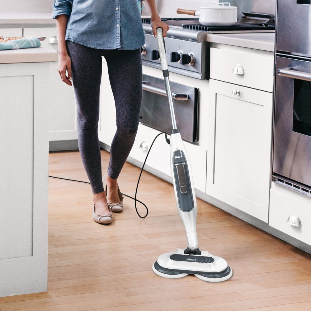 Woman using a Shark Steam and Scrub Mop on a wooden kitchen floor