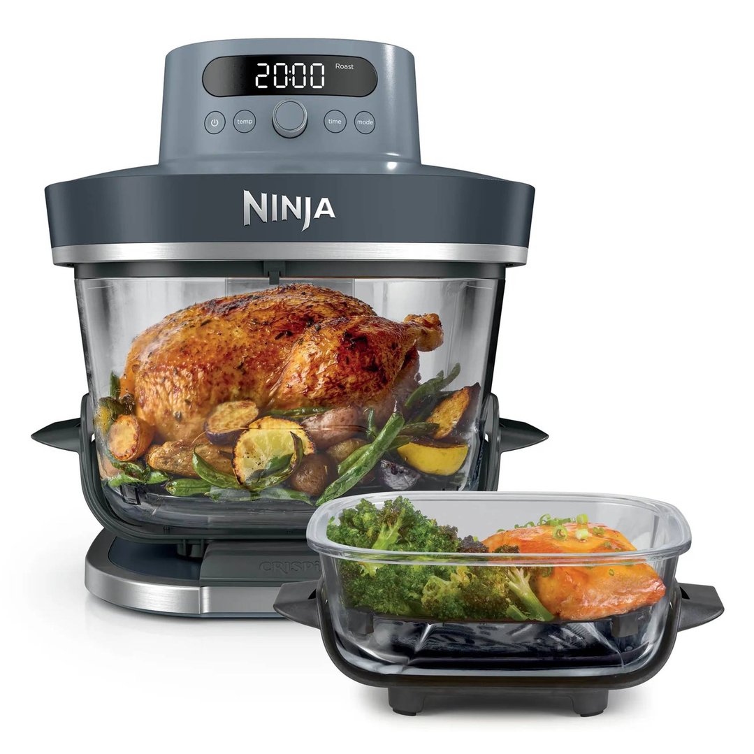 Ninja air fryer roasting a whole chicken and vegetables, with a separate container of food