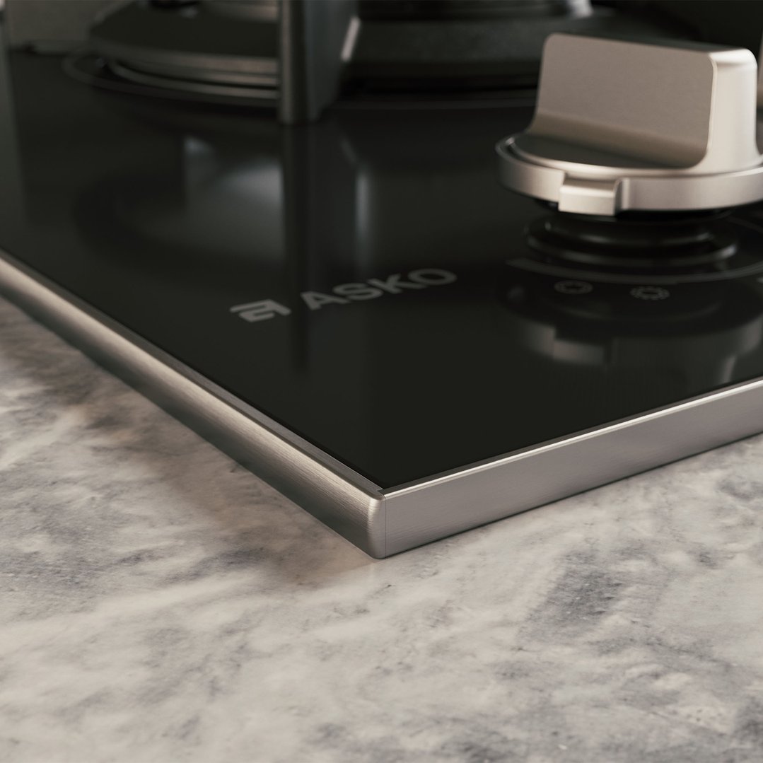 Close up of a black glass cooktop with a control knob on a marble countertop