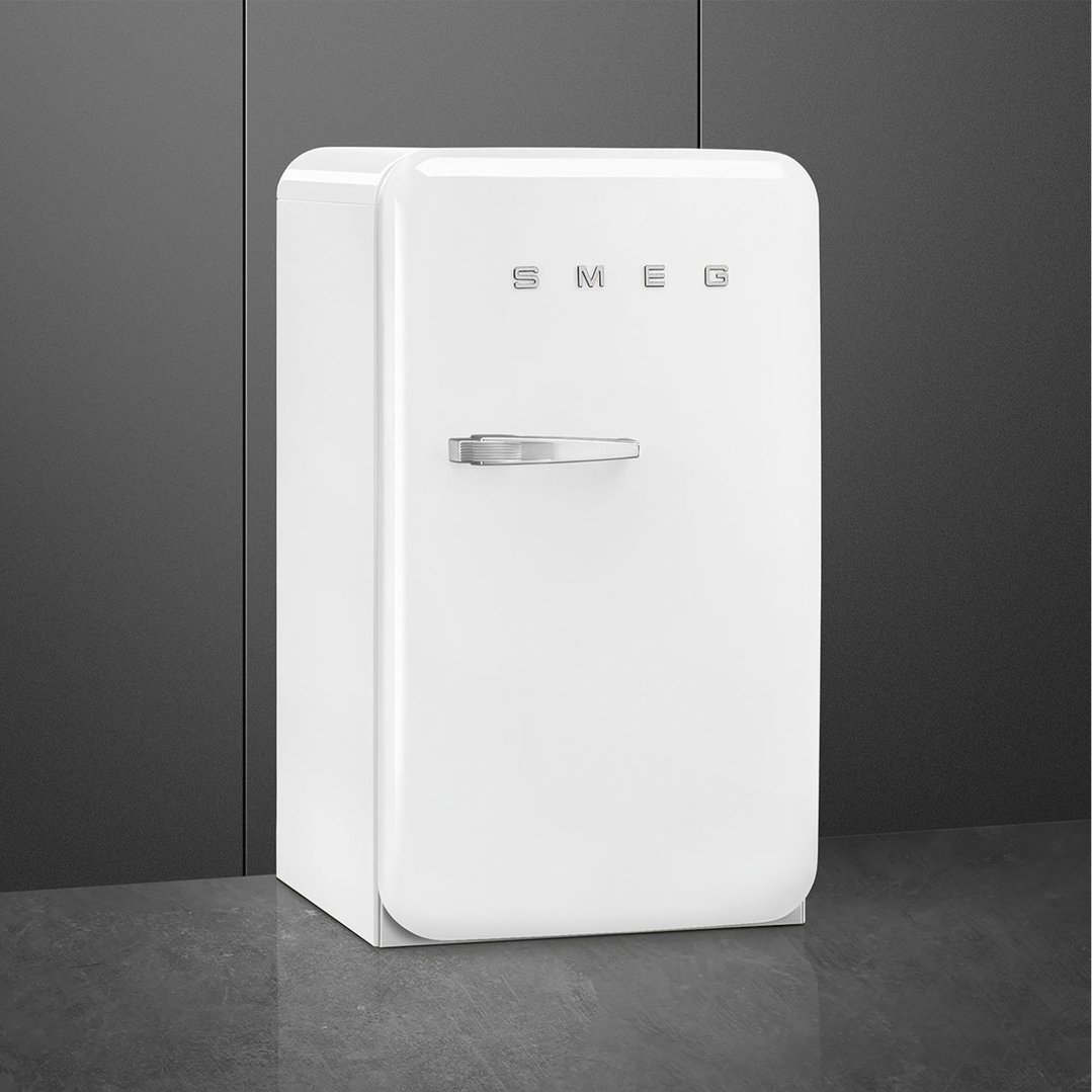 White SMEG refrigerator with right hand hinge in a dark room