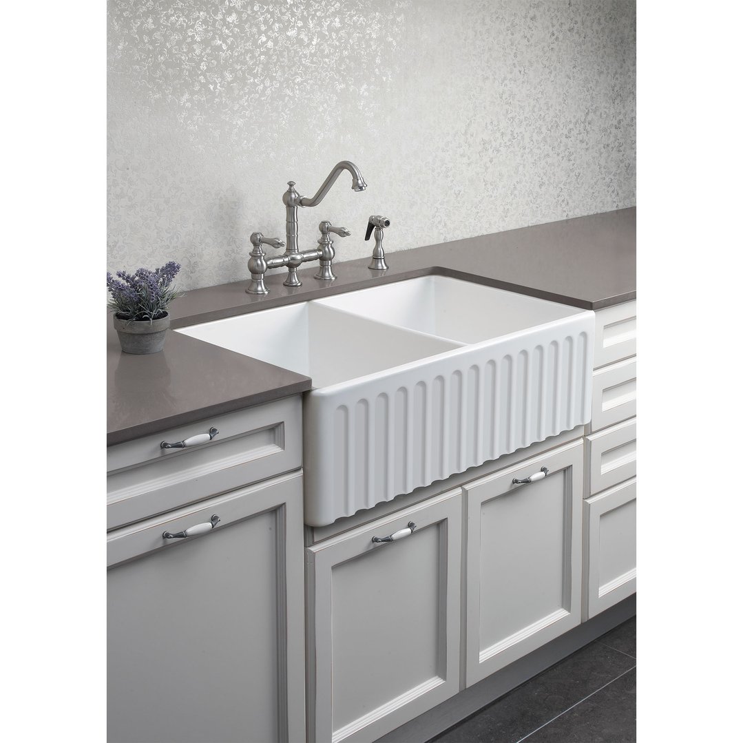 White double bowl fireclay sink installed in a kitchen with grey cabinets