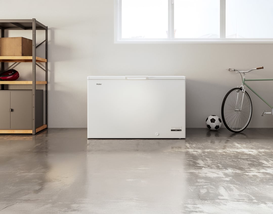 White chest freezer in a garage with shelving, a bicycle, and a soccer ball