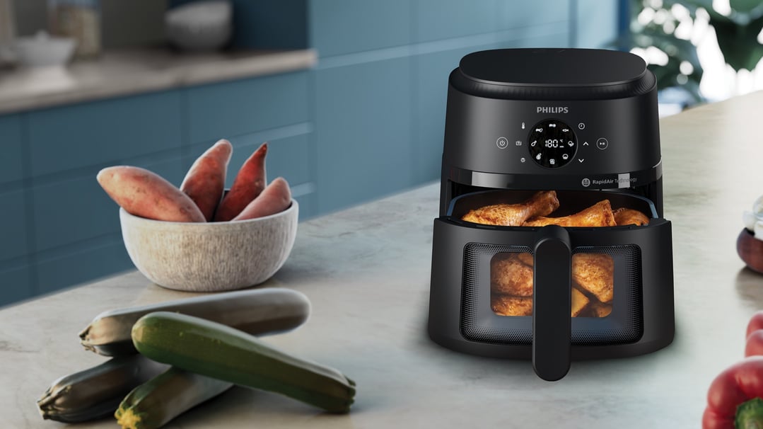 Black Philips airfryer cooking chicken drumsticks on a kitchen counter