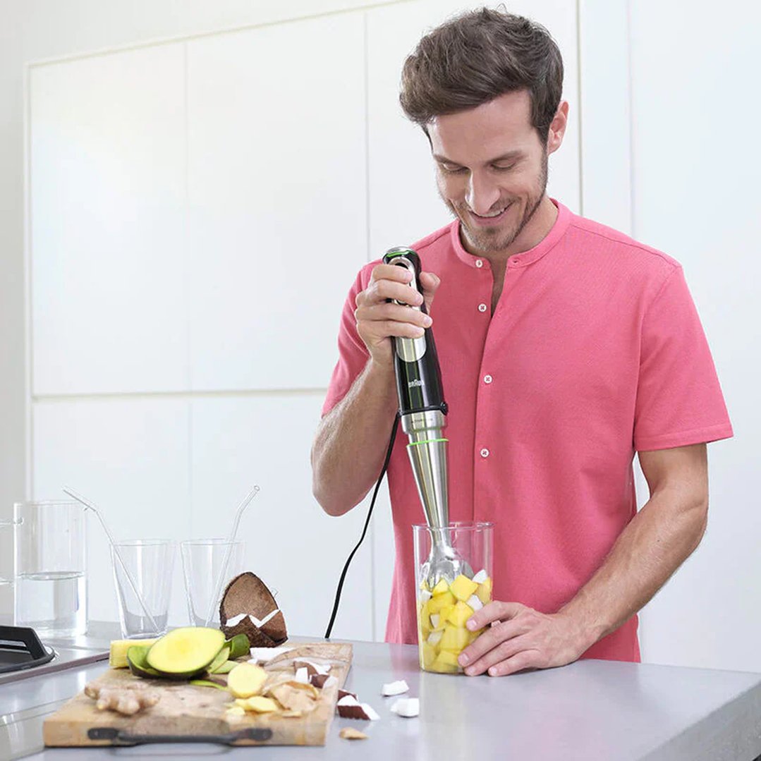 Man using a Braun MultiQuick 9 Hand Blender to blend fruit in a glass
