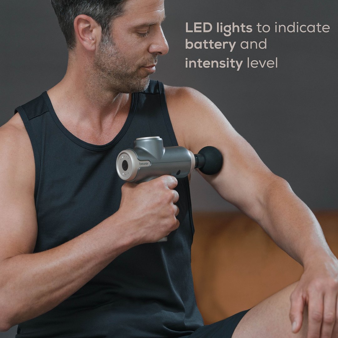 Man using a Beurer Compact Massage Gun Luxe Edition on his arm, with feature text