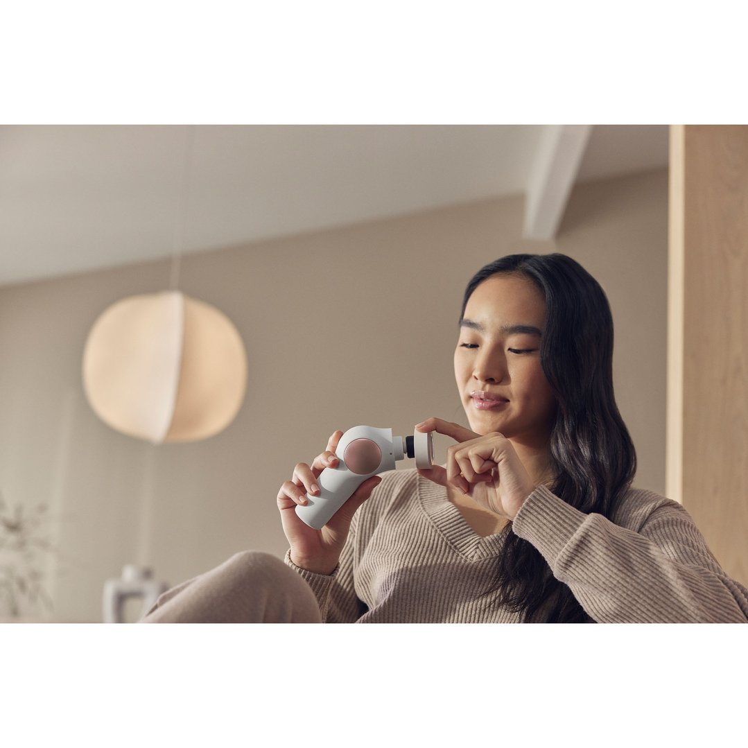 Woman holding a TheraFace PRO Hot & Cold Ring in a living room setting