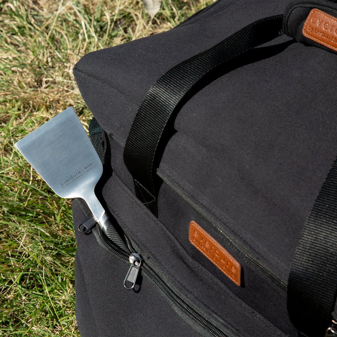 A metal spatula with "everdure" branding partially inserted into a black bag