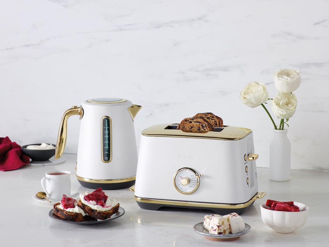 Breville kettle and toaster on a white marble countertop with food and flowers