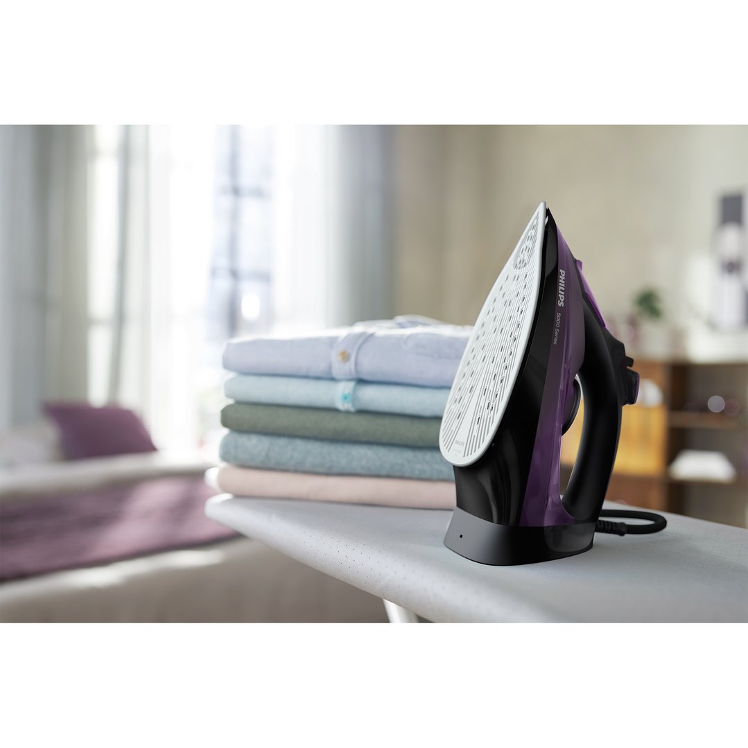Philips 5000 Series Steam Iron on an ironing board with folded clothes