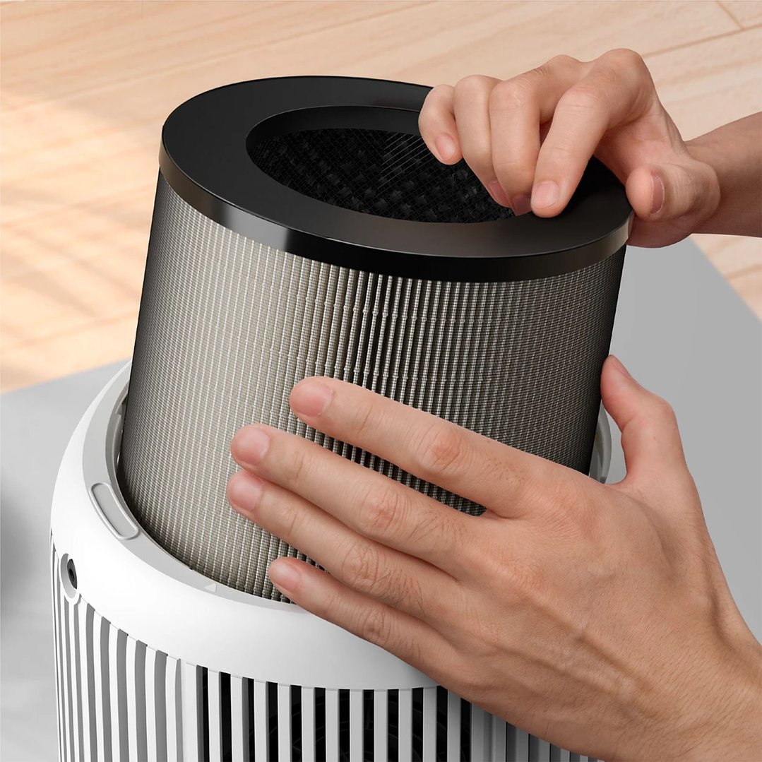 Hands inserting a new air purifier filter into the air purifier unit