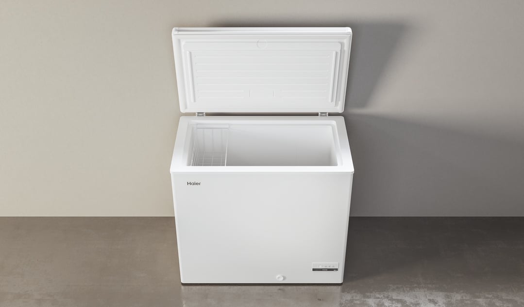 White chest freezer with the lid open, showing the interior and a wire basket
