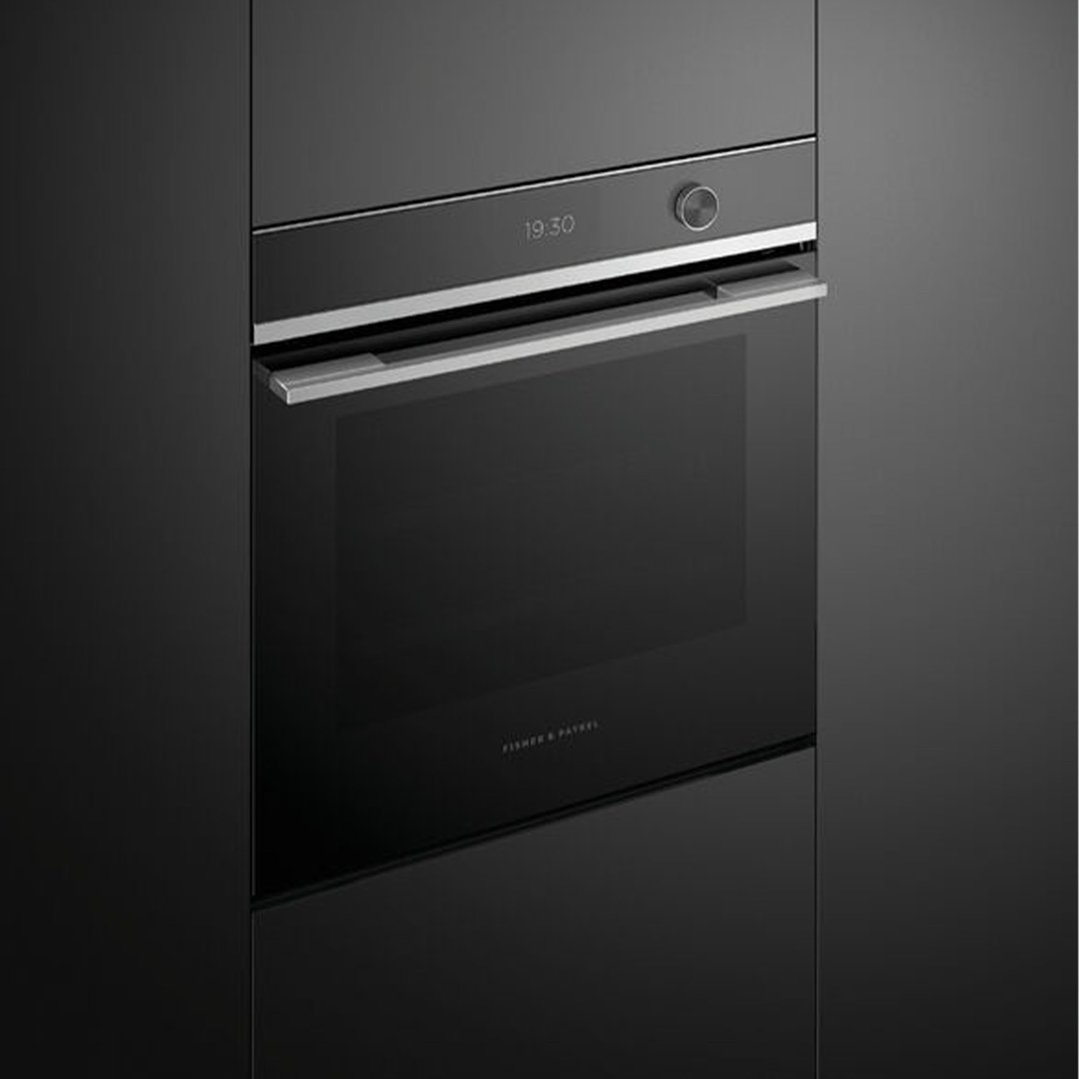 A black Fisher & Paykel compact combi-steam oven built into dark cabinetry