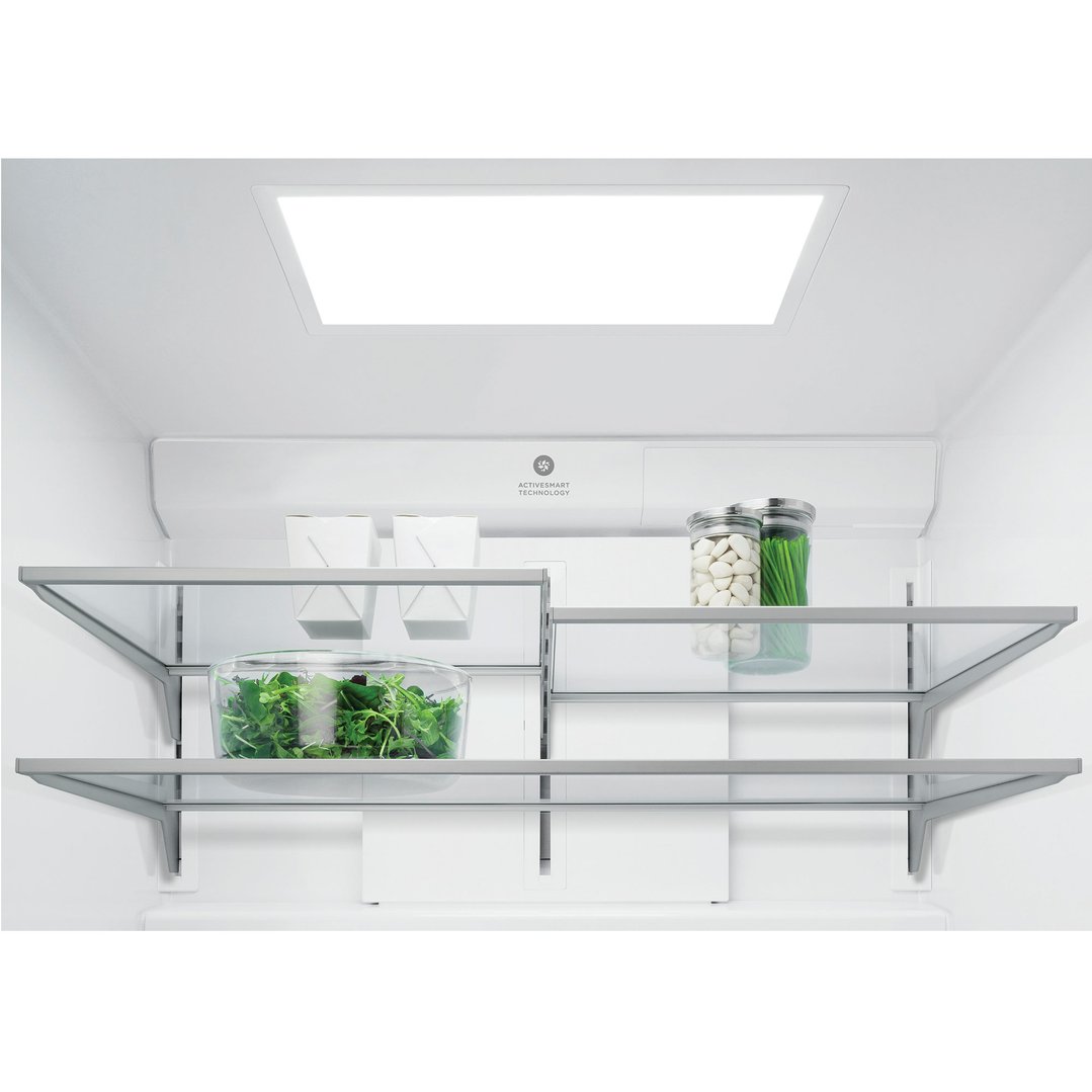Inside a refrigerator with glass shelves, a bowl of salad, and jars of food