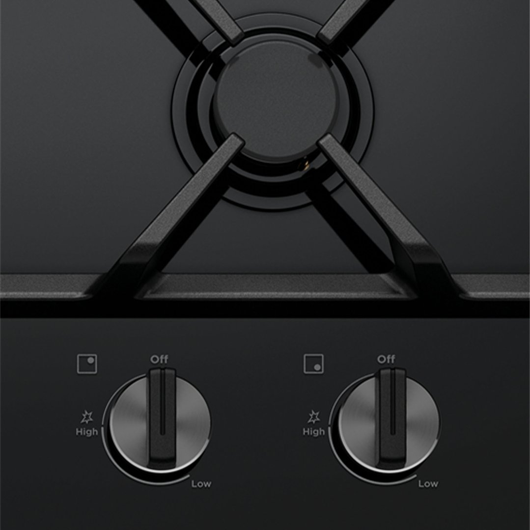 Close-up of a black ceramic glass gas cooktop with two control knobs