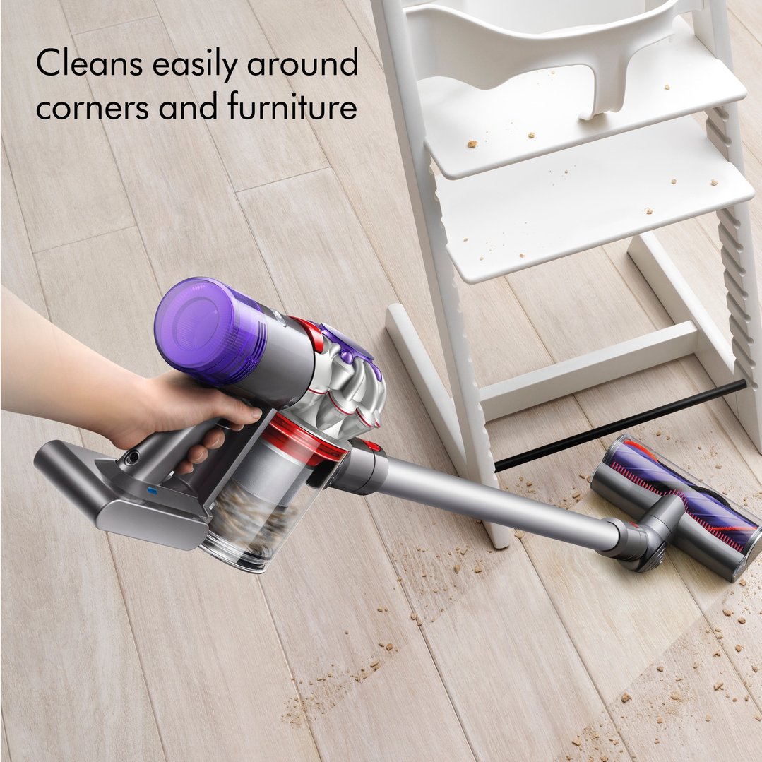 Handheld Dyson handstick vacuum cleaning crumbs from a wooden floor