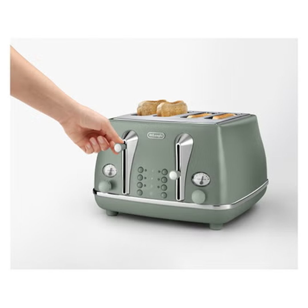 Hand adjusting the settings on a green 4-slice toaster with toast inside