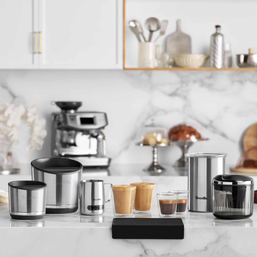 Breville coffee accessories and drinks on a marble countertop in a kitchen