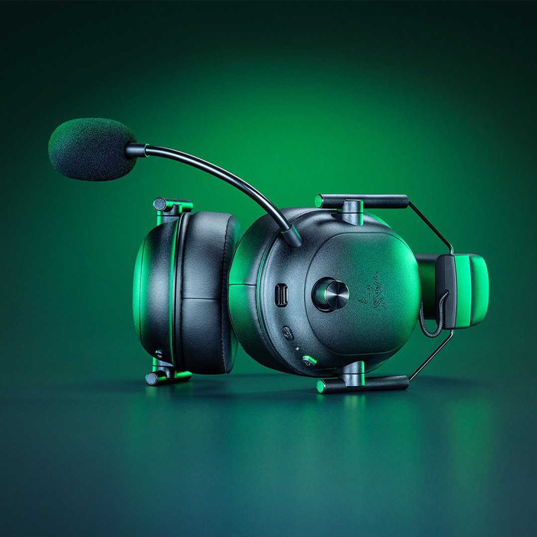 Black Razer headset with microphone on a dark green surface with green lighting