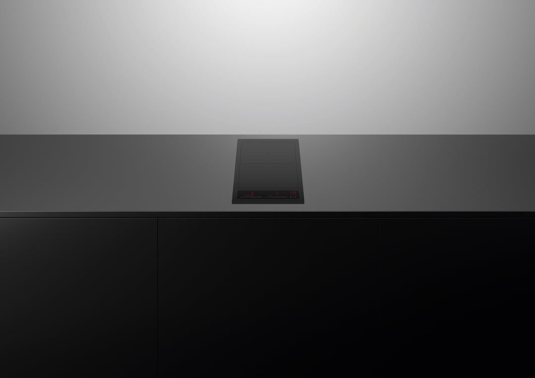 Black induction cooktop with red display lights on a dark countertop in a kitchen