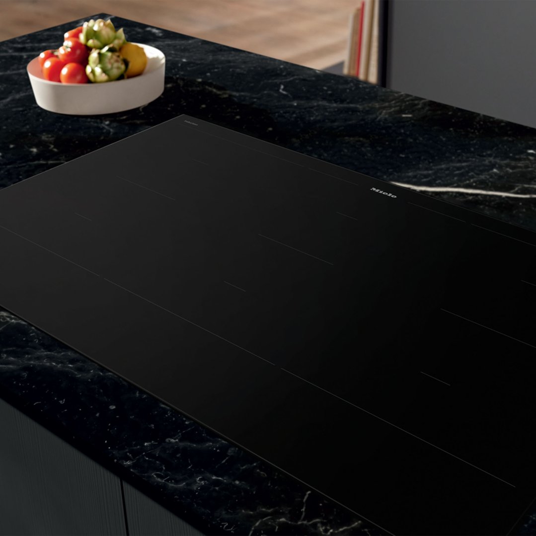 Black induction cooktop with six cooking zones on a black marble countertop