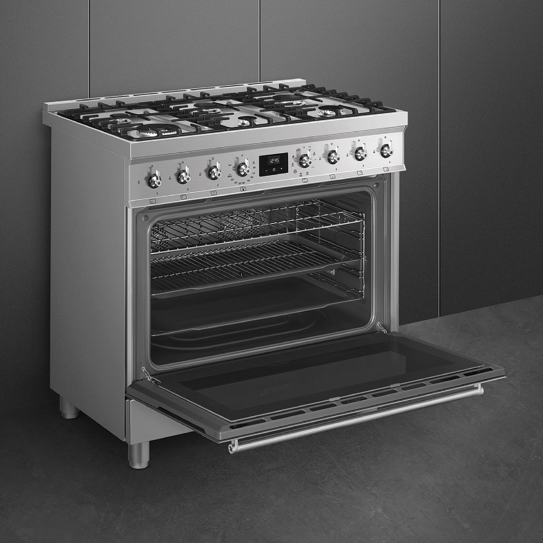 Stainless steel freestanding cooker with oven door open in a modern kitchen setting