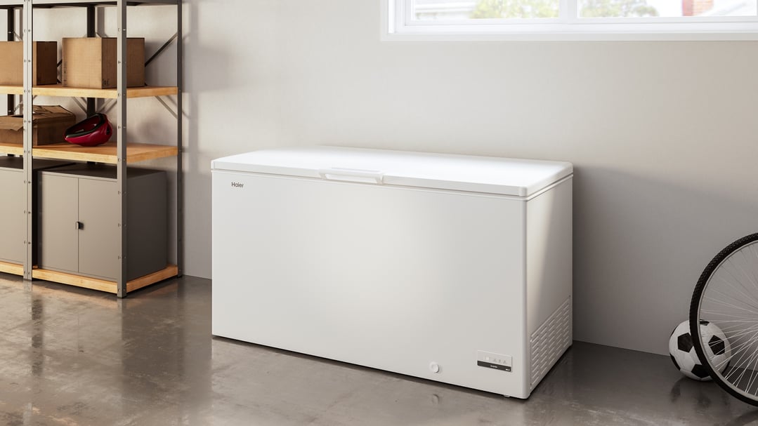 White Haier chest freezer in a garage with shelving and sports equipment