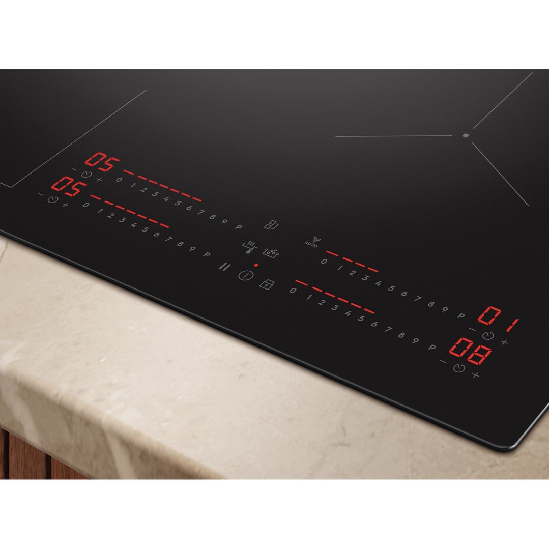 Close up of a black induction cooktop with red digital displays on a countertop