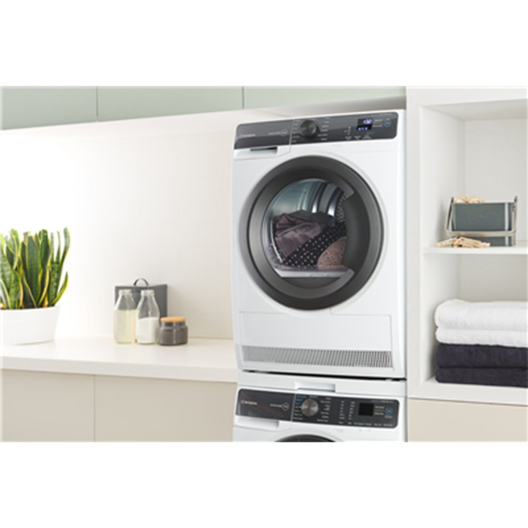 White washer and dryer stacked in a modern laundry room with plants and towels