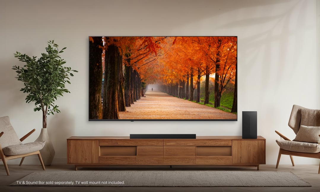 LG QNED70B TV on a wooden console with a soundbar in a living room
