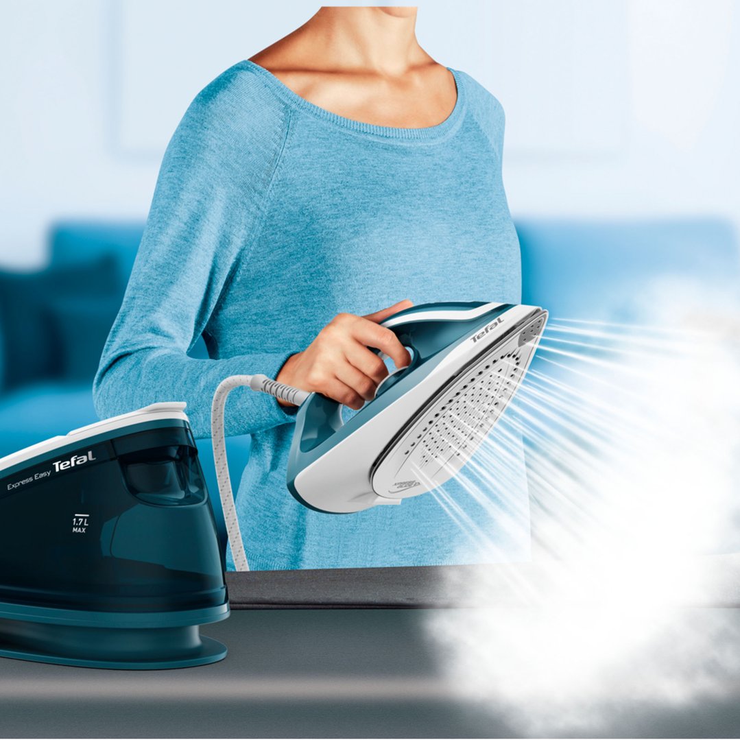 Woman holding a Tefal steam generator iron, with steam coming out