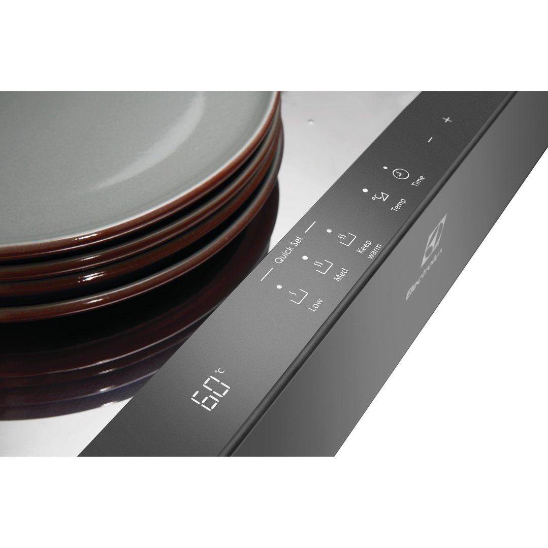 Close up of a warming drawer with plates stacked on top, showing controls