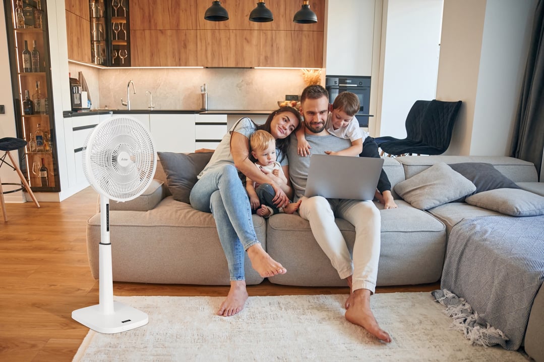 Family on a sofa with a white pedestal fan in a modern living room