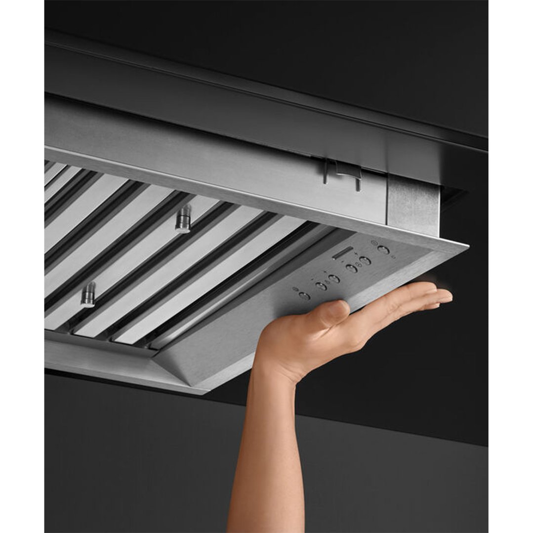 Hand adjusting controls on an integrated insert rangehood in a kitchen
