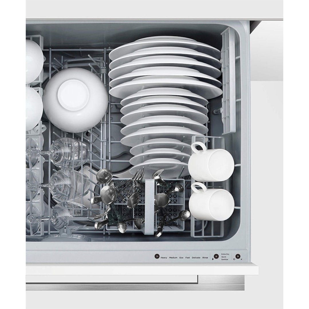 Close up of a fully loaded dishwasher drawer with dishes, glasses, and cutlery