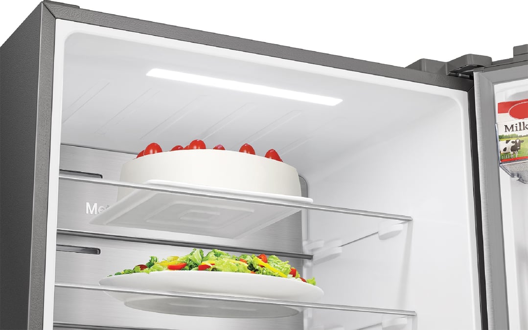 Open fridge interior with cake and salad on shelves, milk carton visible