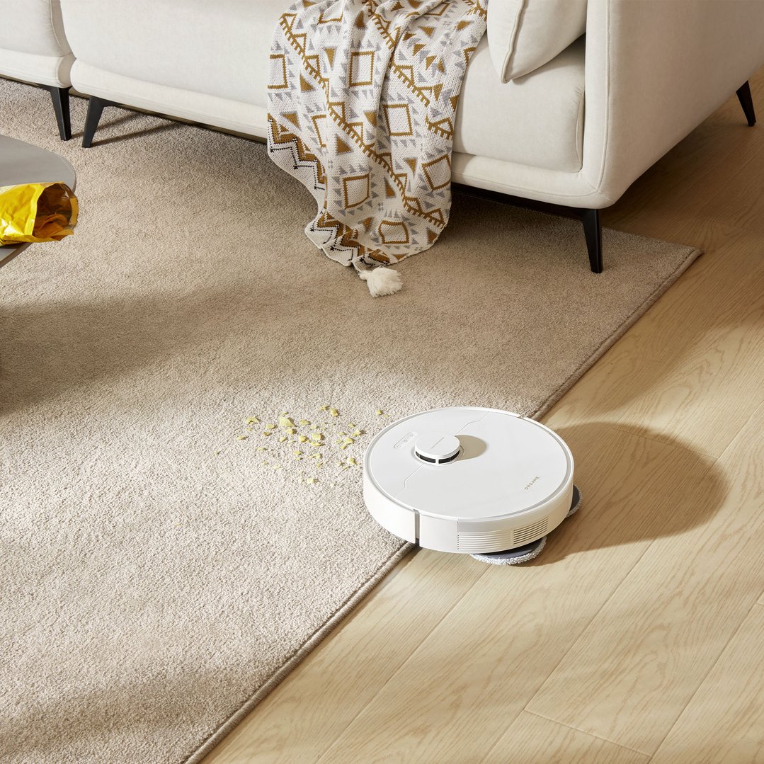 Dreame L10s Plus robot vacuum cleaner on a rug with spilled popcorn