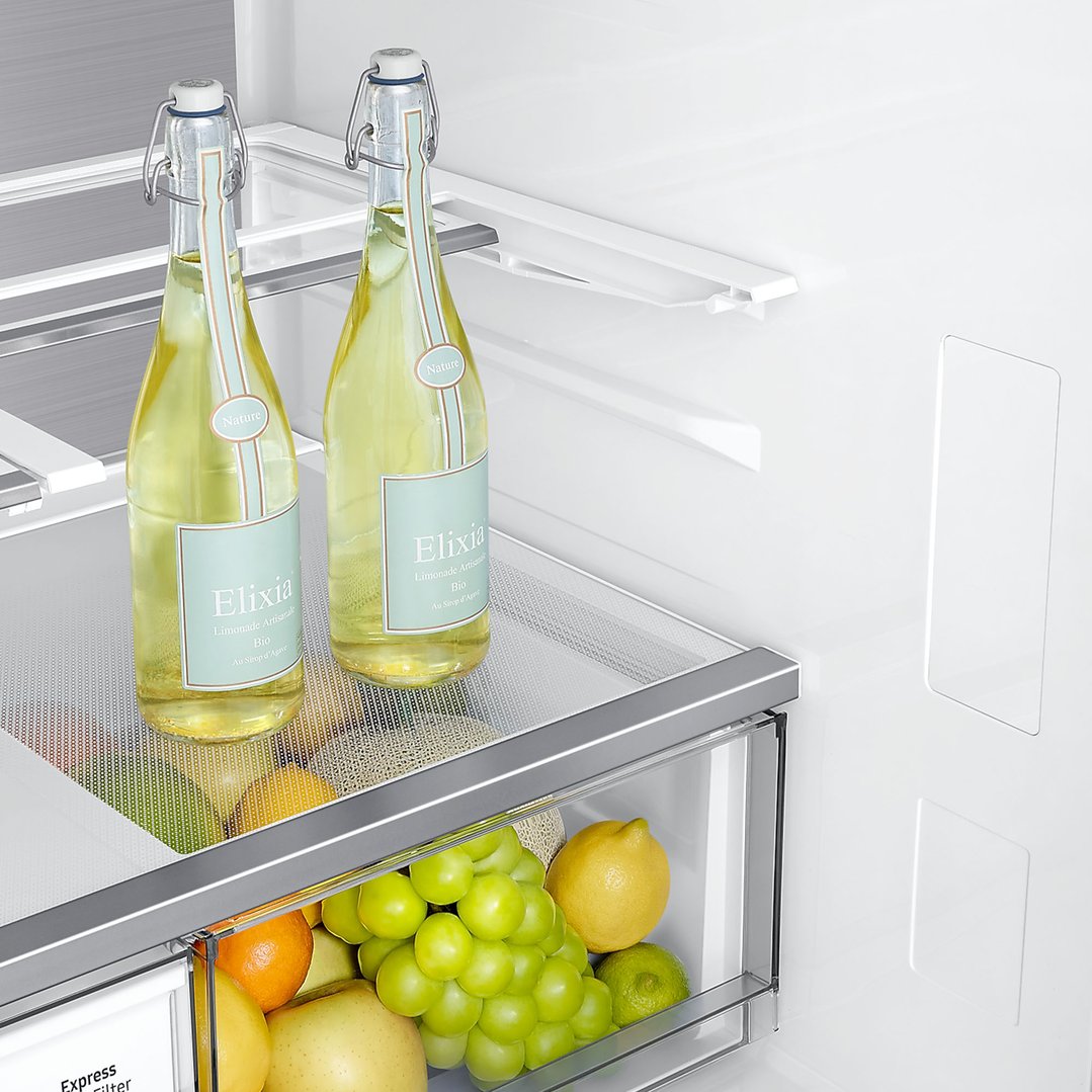 Close-up of the interior of a SAMSUNG French Door Refrigerator with bottles and fruit