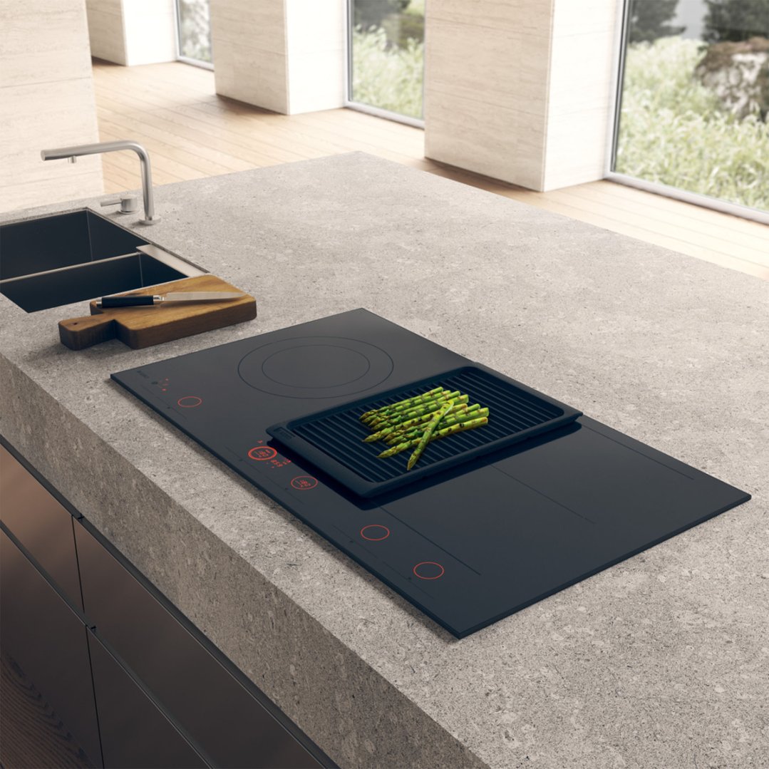 Induction hob cooktop with asparagus on a grill pan in a modern kitchen