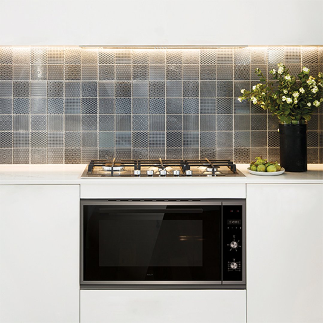 Built-in oven and gas cooktop in a modern kitchen with patterned tile backsplash