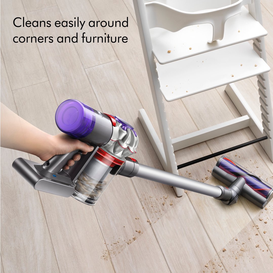 Hand holding a Dyson V8 Advanced Vacuum cleaning crumbs from a wooden floor