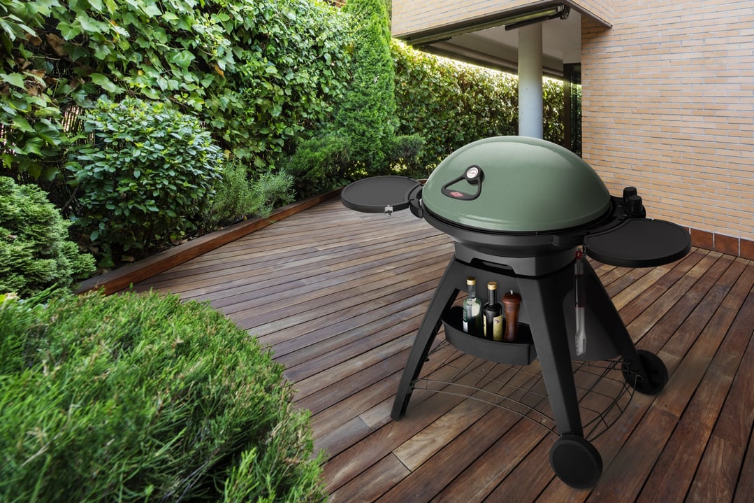 Green barbecue with trolley on a wooden deck in a garden setting
