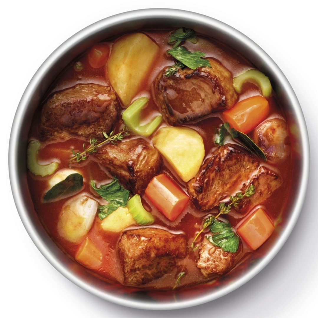 Overhead view of a stew with meat, potatoes, carrots, and celery in a pot